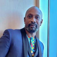 A headshot of a men wearing a blue suite and a colorful shirt